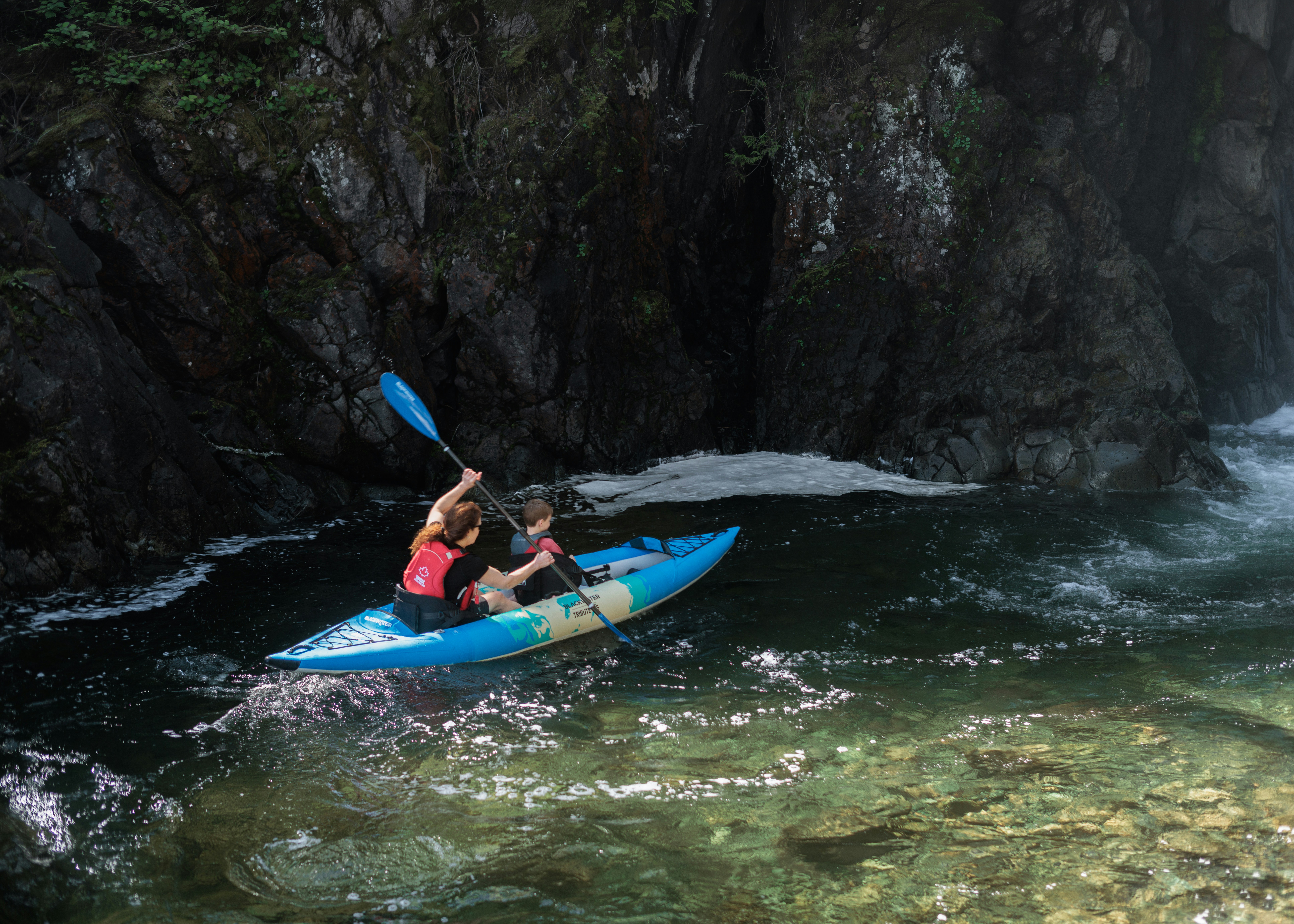 Two people kayaking together through a dramatic river gorge